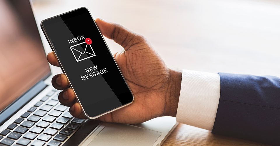 A man holding a mobile phone and looking at a new message