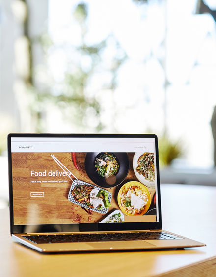 WordPress Development Services showing a responsive food delivery website design on a laptop for business growth